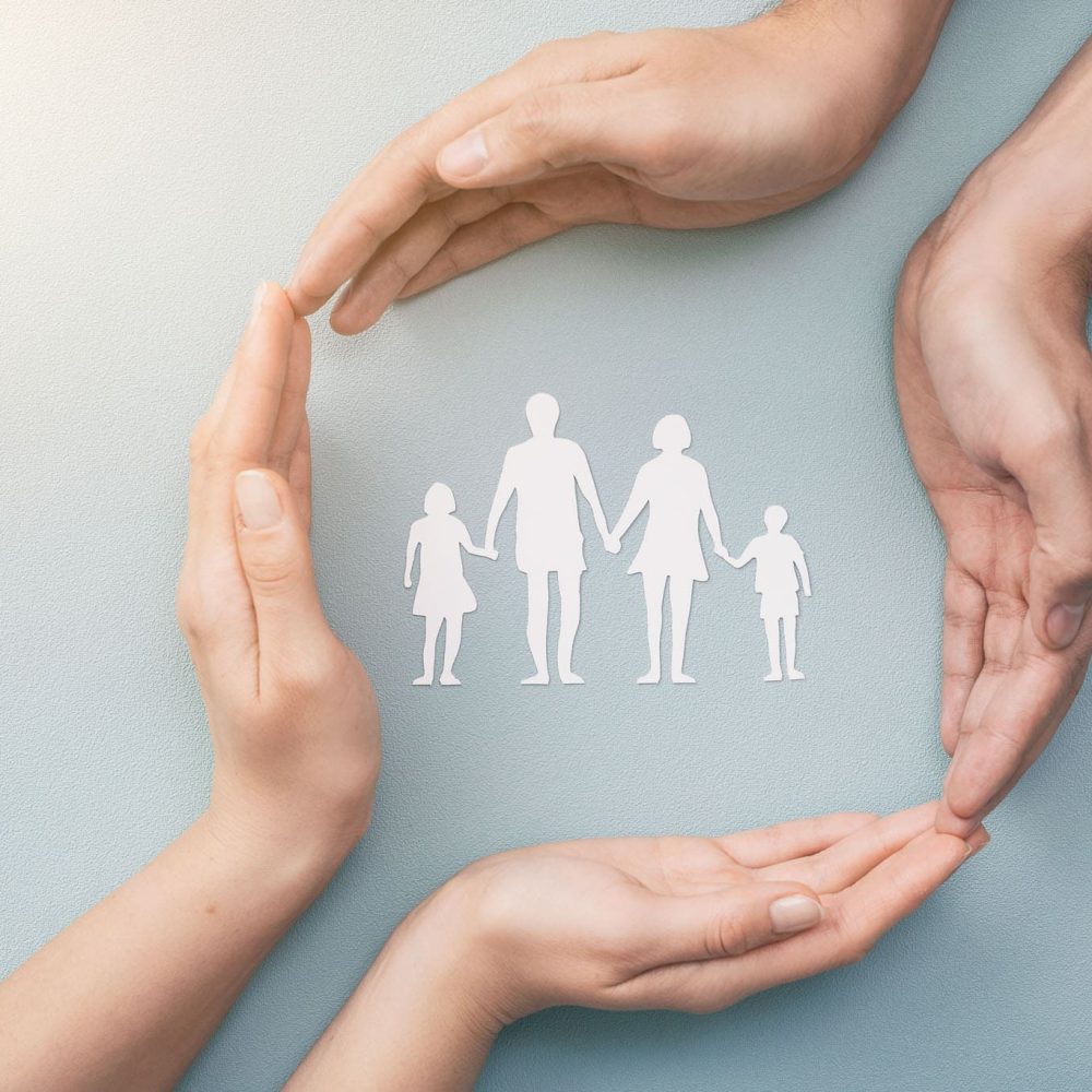 Hands with cut out paper silhouette on table. Family care concept.